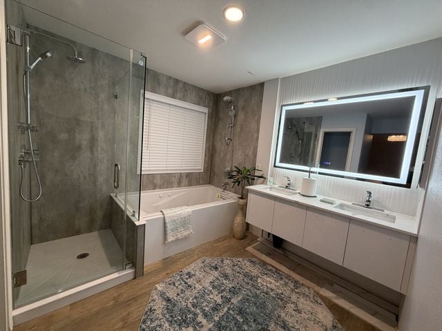 Completed full bathroom with a glass walk-in shower, built-in soaking tub, floating double vanity, and a large illuminated mirror.