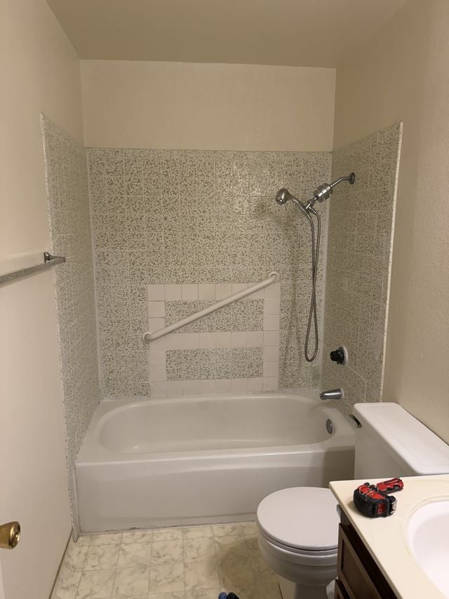 Bathtub and shower with a tiled surround, a recessed niche, a handheld shower, and an adjacent vanity.