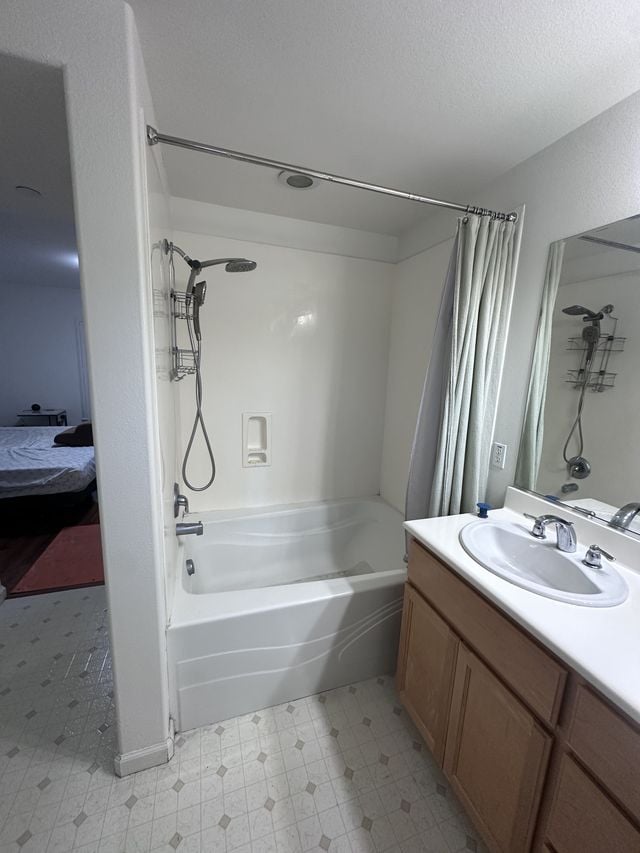 Existing bathroom with a bathtub and shower, a curtain rod, a wood vanity, and a large mirror.