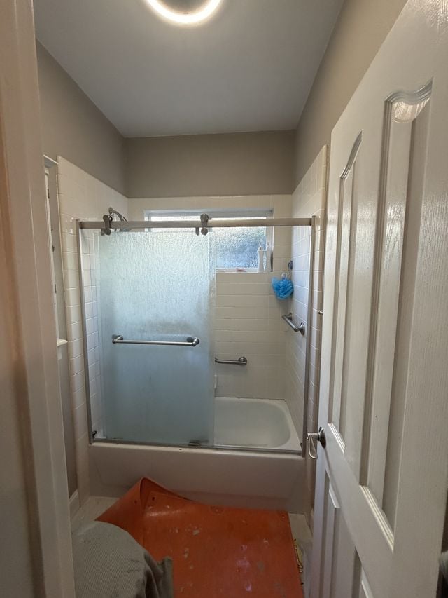 Bathtub with frosted sliding glass doors and a grab bar, with floor protection during installation.