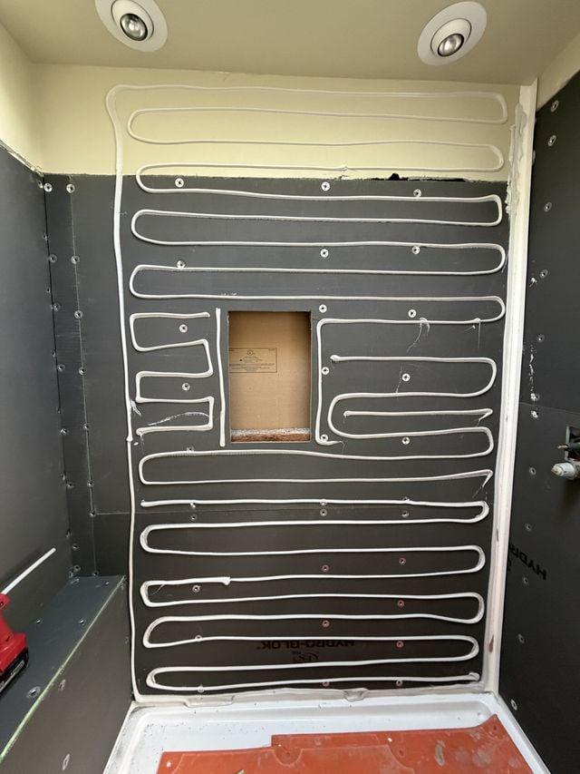 Shower walls covered with black waterproofing membrane before wall-panel installation.