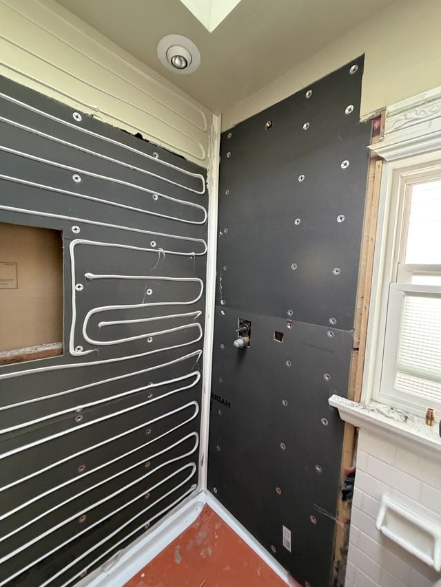 Bathroom walls covered with waterproofing membrane, with a window and floor protection during preparation.